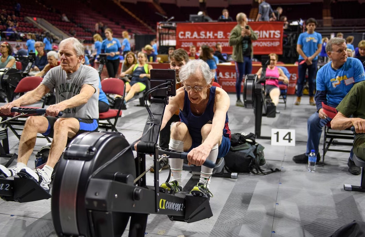 A 93-year-old man indoor rowing at a competition.